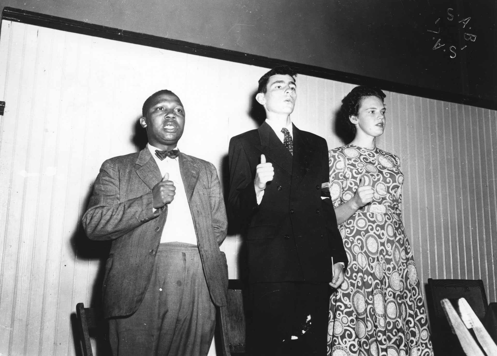 Joseph Nkatlo, Albie Sachs and Mary Butcher giving the closed fists with upraised thumb salute at a Defiance Campaign meeting at the Drill Hall in Cape Town on 12 April 1952, when it was announced  that Sachs and Butcher were going to take part in the Defiance Campaign. They were among the first white South Africans to join the campaign in Cape Town.