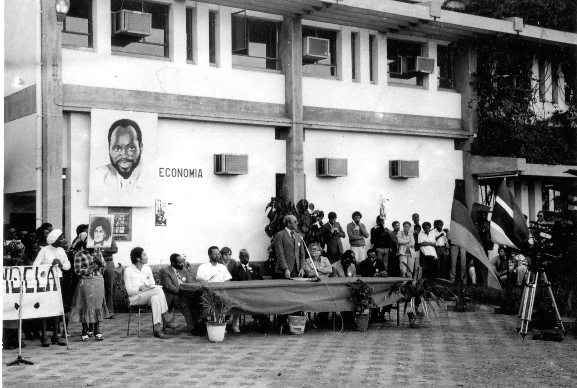 Memorial for Ruth First at Eduardo Mondlane University, Maputo. Albie seated in front of portrait. At table: Jacob Zuma, interpreter standing, Moses Mabhida, Fernando Ganhao (rector), Joe Slovo and Malumi.