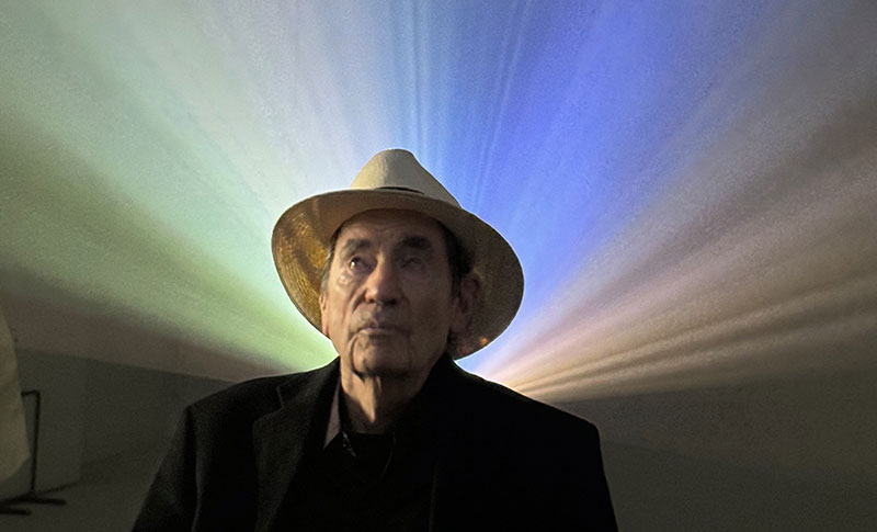 Albie awith colour from projections of archival footage behind him